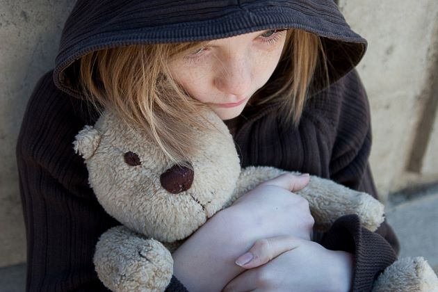 Bild: Trauriges Kind mit Teddy im Arm